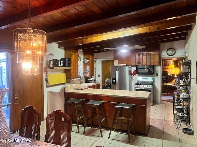 kitchen with stainless steel appliances, beamed ceiling, a breakfast bar, and light tile patterned floors