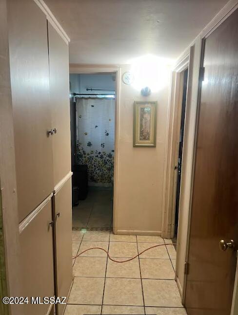 corridor with crown molding and light tile patterned floors