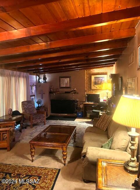 living room featuring beamed ceiling, wood ceiling, and brick wall