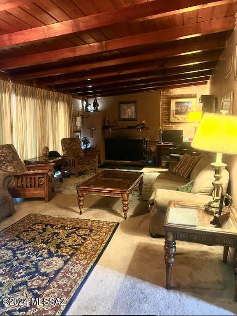 living room featuring beam ceiling, carpet, brick wall, and wooden ceiling