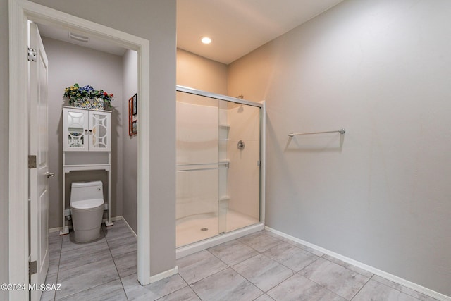 bathroom featuring tile patterned flooring, a shower with shower door, and toilet