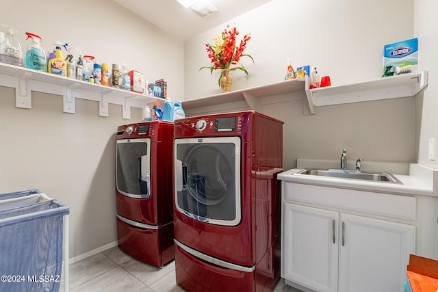 clothes washing area with sink, light tile patterned floors, cabinets, and washer and dryer