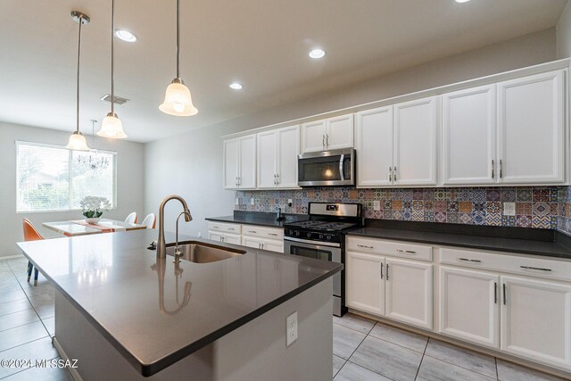 kitchen with sink, a kitchen island with sink, hanging light fixtures, stainless steel appliances, and white cabinets