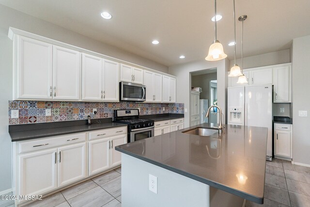 kitchen with pendant lighting, sink, white cabinetry, stainless steel appliances, and an island with sink