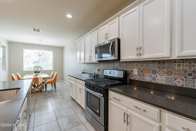 kitchen featuring light tile patterned floors, pendant lighting, stainless steel appliances, decorative backsplash, and white cabinets