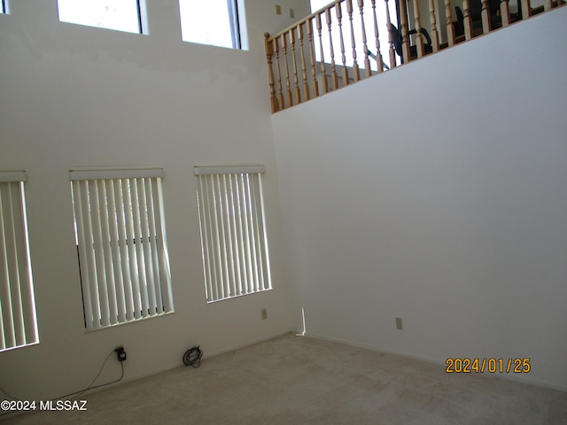 spare room featuring carpet floors and a high ceiling