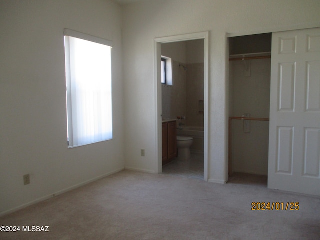 unfurnished bedroom with ensuite bath, multiple windows, and carpet flooring