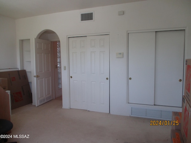 unfurnished bedroom featuring multiple closets and carpet flooring