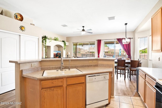 kitchen with sink, a kitchen island with sink, white dishwasher, and decorative light fixtures