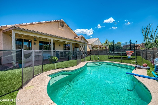 view of swimming pool with a trampoline and a yard