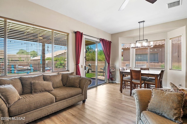 living room featuring ceiling fan with notable chandelier and light hardwood / wood-style flooring