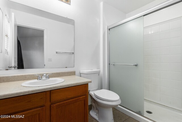 bathroom featuring a shower with shower door, tile patterned floors, toilet, and vanity