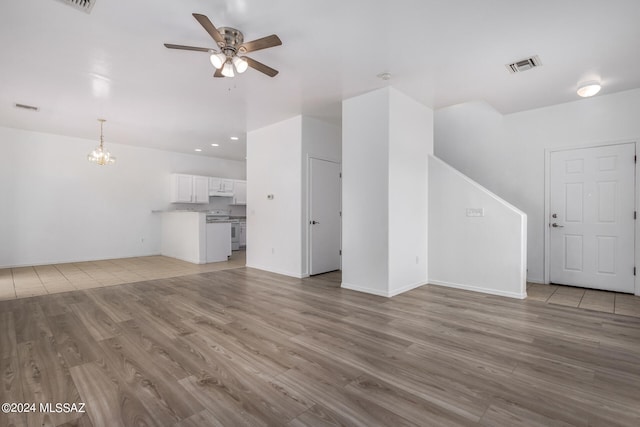 unfurnished living room with light hardwood / wood-style flooring and ceiling fan with notable chandelier