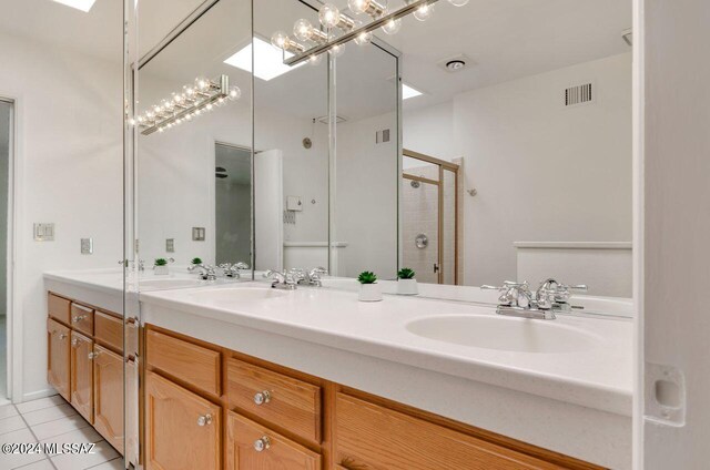 bathroom with a skylight, tile patterned floors, a shower with door, and vanity