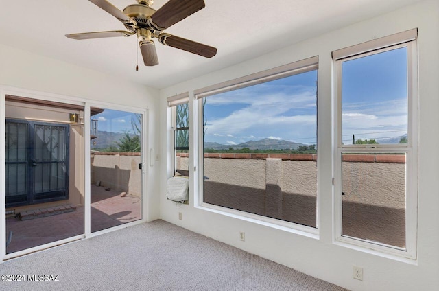 unfurnished sunroom featuring a mountain view and a ceiling fan