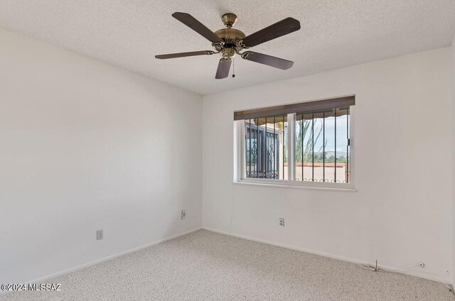 carpeted spare room featuring a textured ceiling and ceiling fan