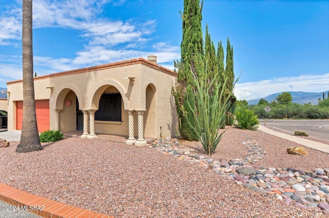 mediterranean / spanish home with a garage, a mountain view, and stucco siding