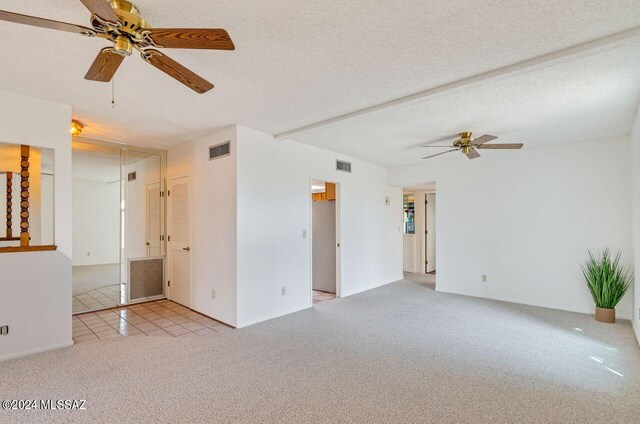 carpeted spare room featuring ceiling fan and a textured ceiling