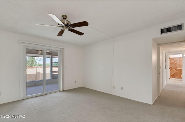 empty room featuring a textured ceiling, ceiling fan, carpet, and visible vents