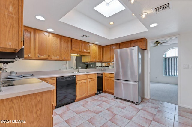 kitchen with freestanding refrigerator, black dishwasher, visible vents, and a tray ceiling