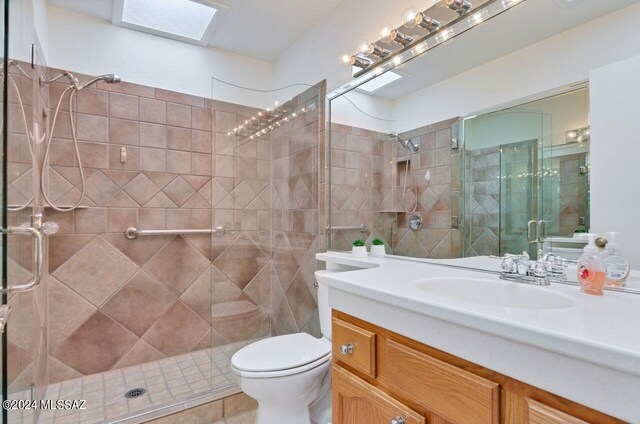 bathroom with a skylight, tile patterned floors, vanity, toilet, and walk in shower