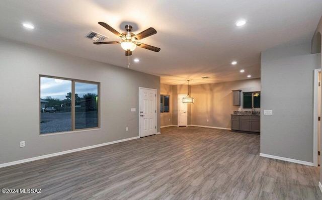 unfurnished living room with ceiling fan and hardwood / wood-style flooring