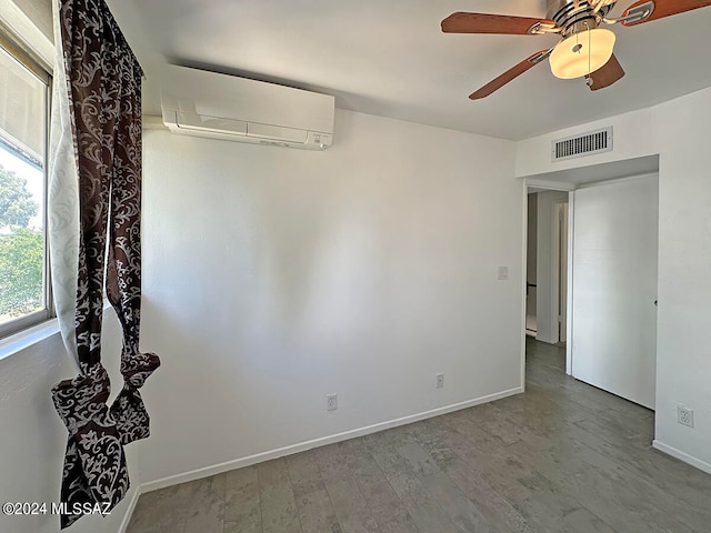 spare room with a wall mounted air conditioner, ceiling fan, and wood-type flooring