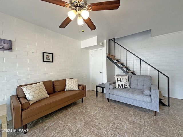 living room featuring ceiling fan and brick wall