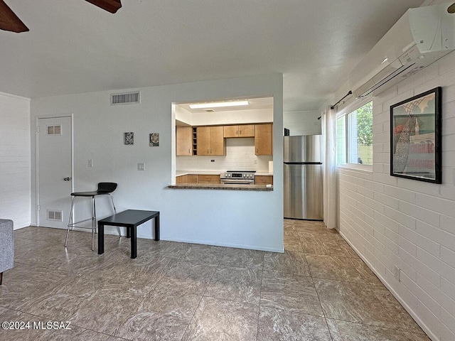 kitchen with appliances with stainless steel finishes, a breakfast bar, brick wall, kitchen peninsula, and decorative backsplash