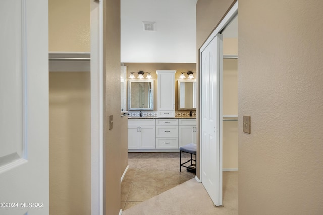 full bathroom featuring a textured wall, visible vents, a spacious closet, tile patterned floors, and double vanity