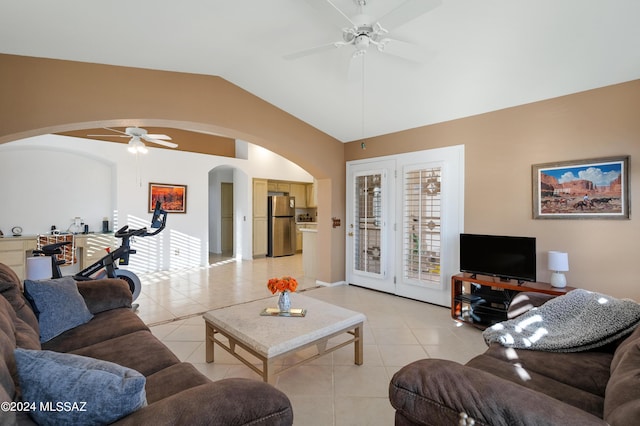 living area with light tile patterned floors, vaulted ceiling, arched walkways, and a ceiling fan