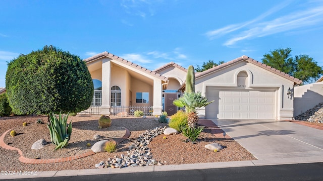 mediterranean / spanish home with concrete driveway, an attached garage, a tile roof, and stucco siding