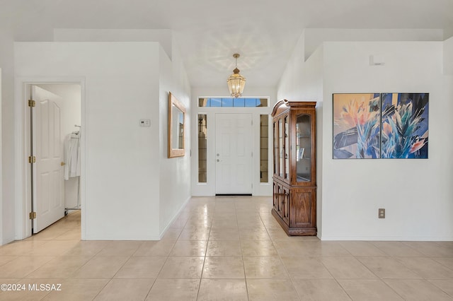 foyer with baseboards, a chandelier, and light tile patterned flooring