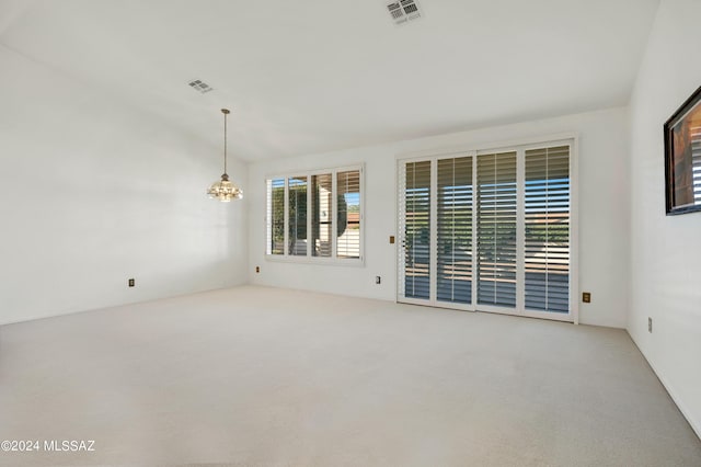 spare room with vaulted ceiling, light carpet, a chandelier, and visible vents