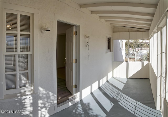 unfurnished sunroom with vaulted ceiling with beams