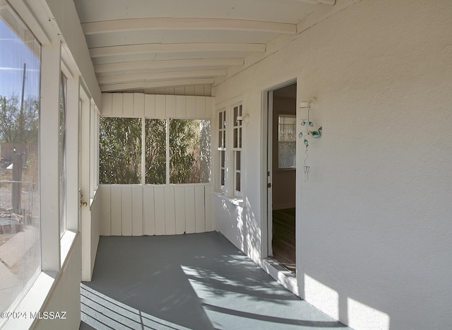 unfurnished sunroom featuring lofted ceiling with beams