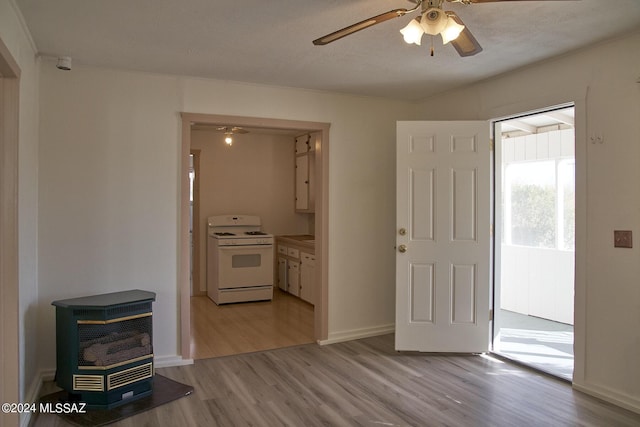 interior space with ceiling fan, light hardwood / wood-style floors, heating unit, and a wood stove