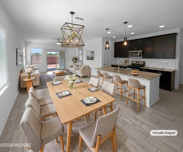 dining space featuring light hardwood / wood-style flooring, a notable chandelier, and sink