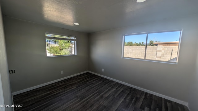 unfurnished room featuring dark wood-type flooring and a textured ceiling