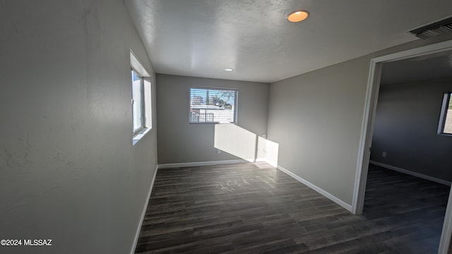 spare room featuring dark hardwood / wood-style floors and a textured ceiling