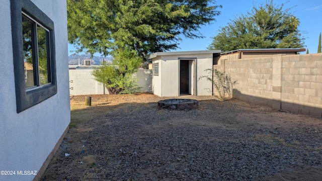 view of yard featuring a storage shed and an outdoor fire pit