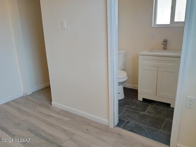 bathroom with hardwood / wood-style flooring, vanity, and toilet