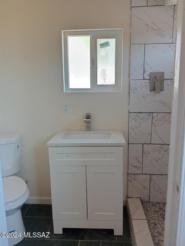 bathroom featuring tile patterned flooring, vanity, tiled shower, and toilet