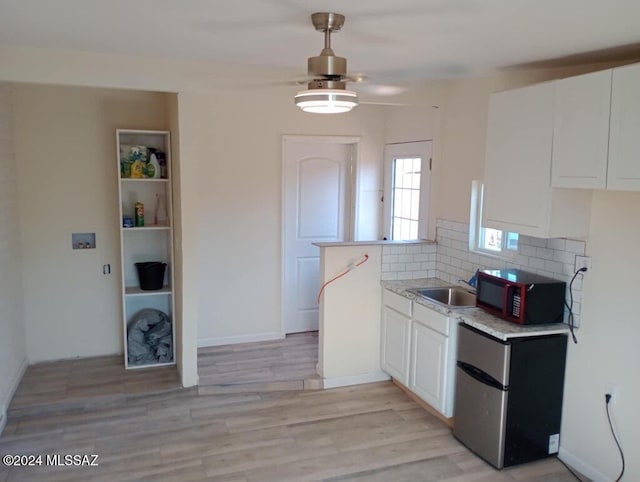 kitchen featuring sink, stainless steel refrigerator, tasteful backsplash, white cabinets, and light wood-type flooring