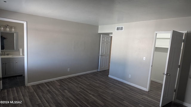 unfurnished bedroom with sink, dark wood-type flooring, and connected bathroom