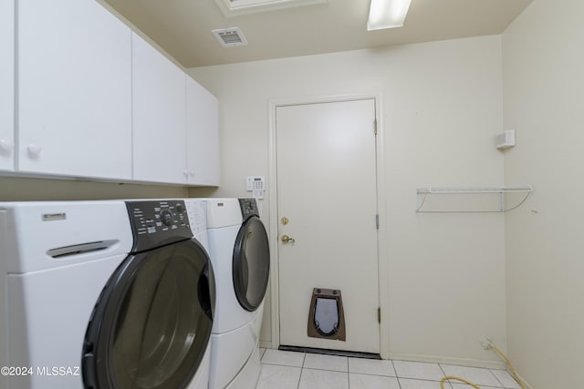 laundry room with washer and clothes dryer, light tile patterned floors, and cabinets