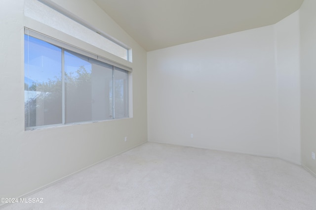 carpeted spare room featuring vaulted ceiling