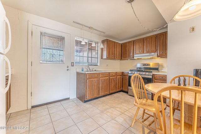 kitchen featuring sink, gas range, white fridge, and light tile patterned flooring