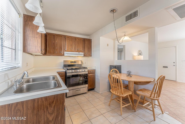 kitchen featuring sink, decorative light fixtures, stainless steel gas range, and light tile patterned flooring