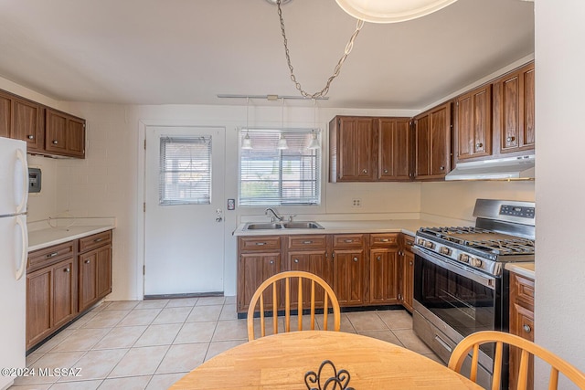 kitchen featuring sink, stainless steel gas range oven, white refrigerator, and light tile patterned flooring